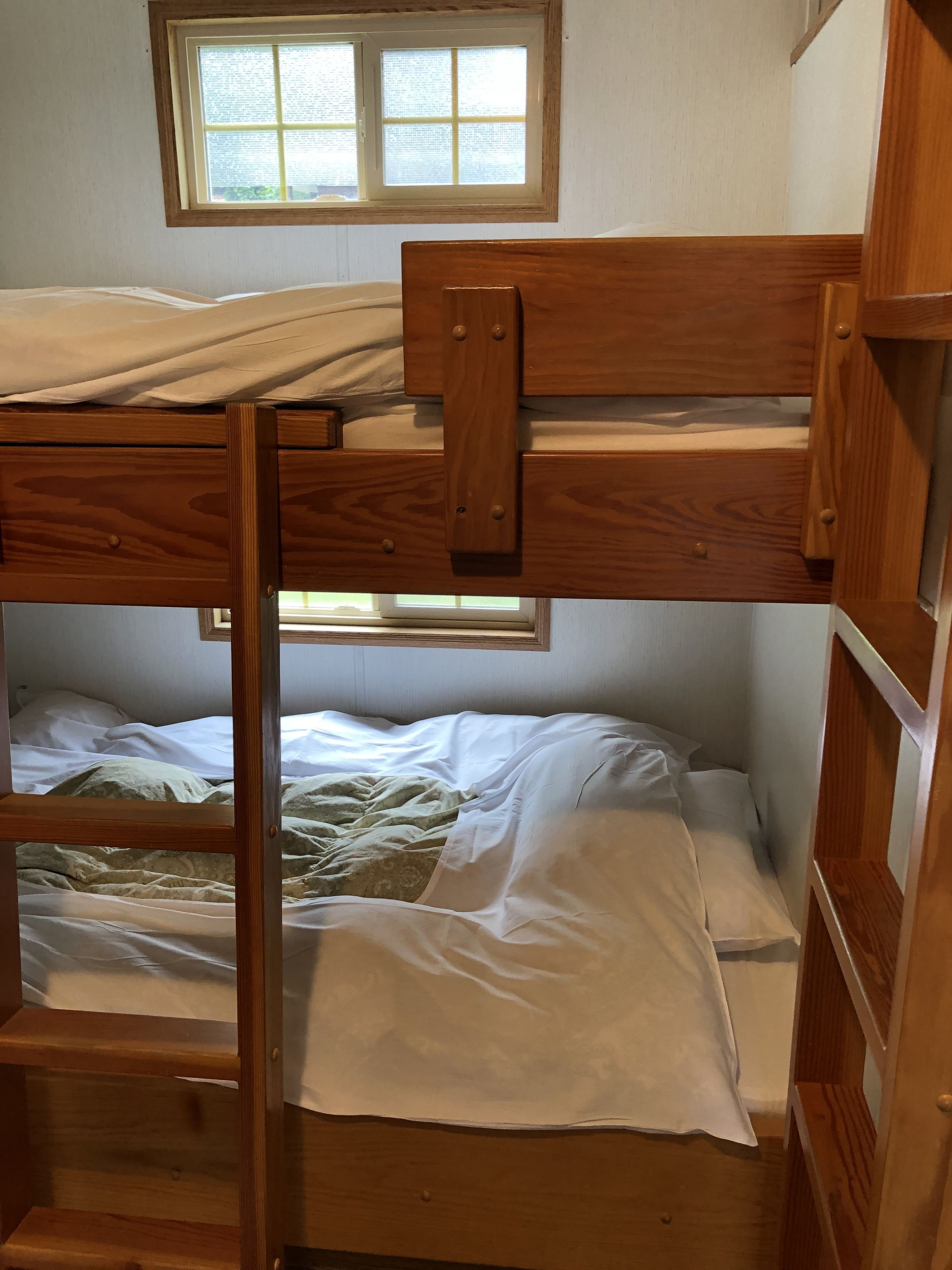 A bunk bed with a wooden frame and white bedding.