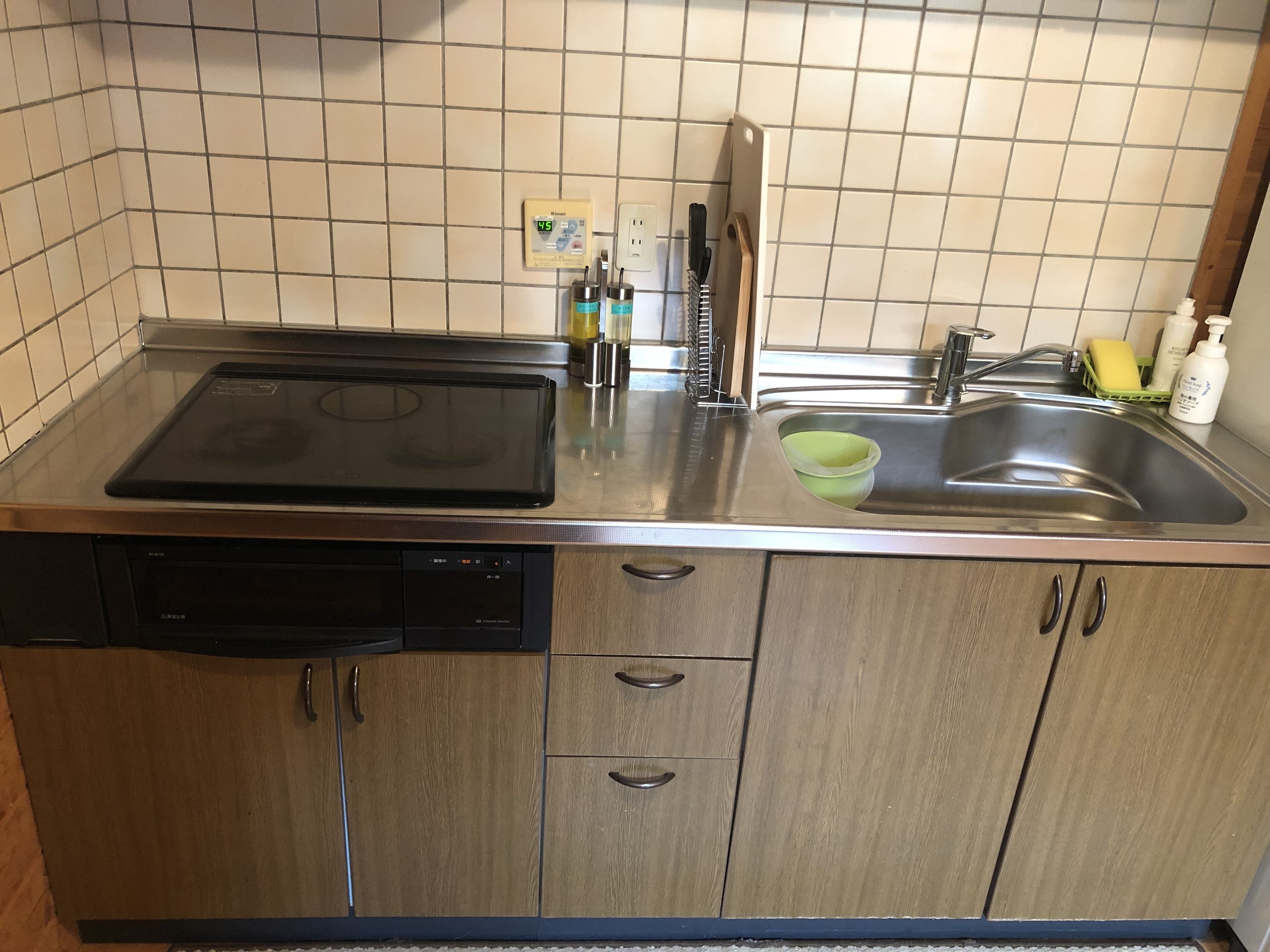 Une cuisine équipée d’un lave-vaisselle, d’une cuisinière, d’un évier et de meubles de rangement en bois.