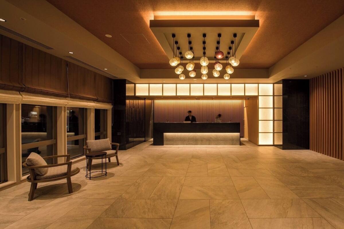 Eine großzügige Lobby mit Empfangstresen, Sitzgelegenheiten und einem modernen Kronleuchter.