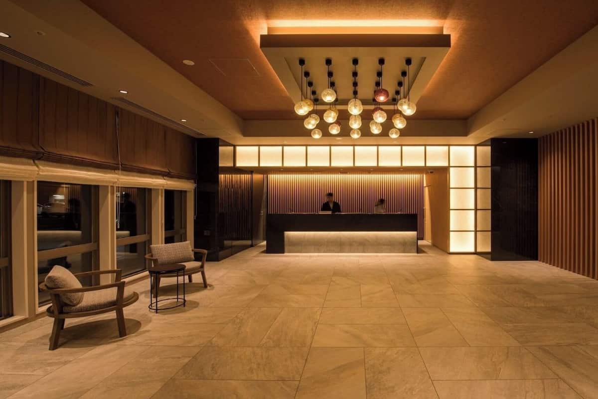 A spacious lobby with a reception desk, seating area, and a modern chandelier.