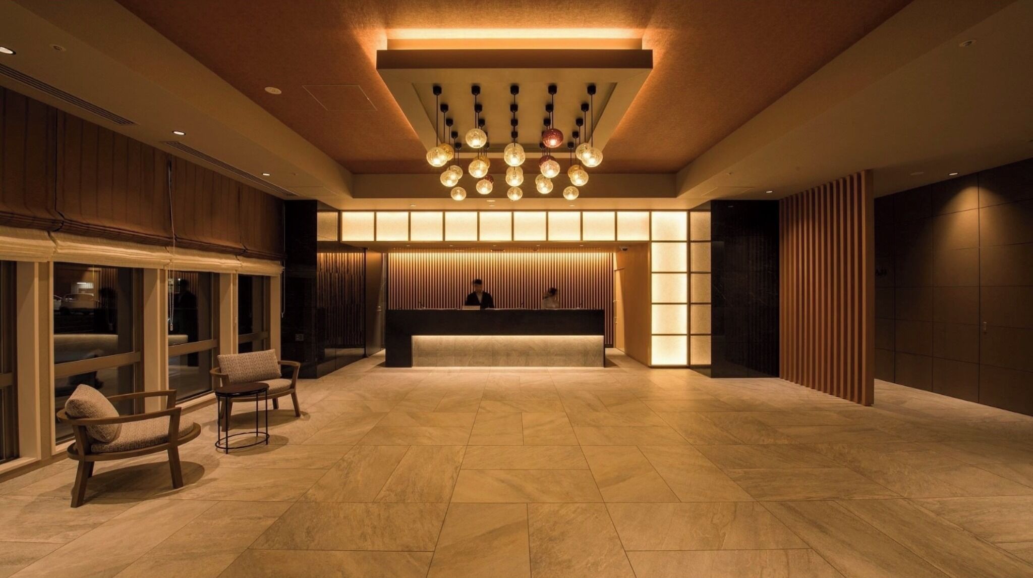 A spacious lobby with a reception desk, seating area, and a modern chandelier.