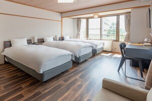A hotel room with two beds, a desk, and a chair.