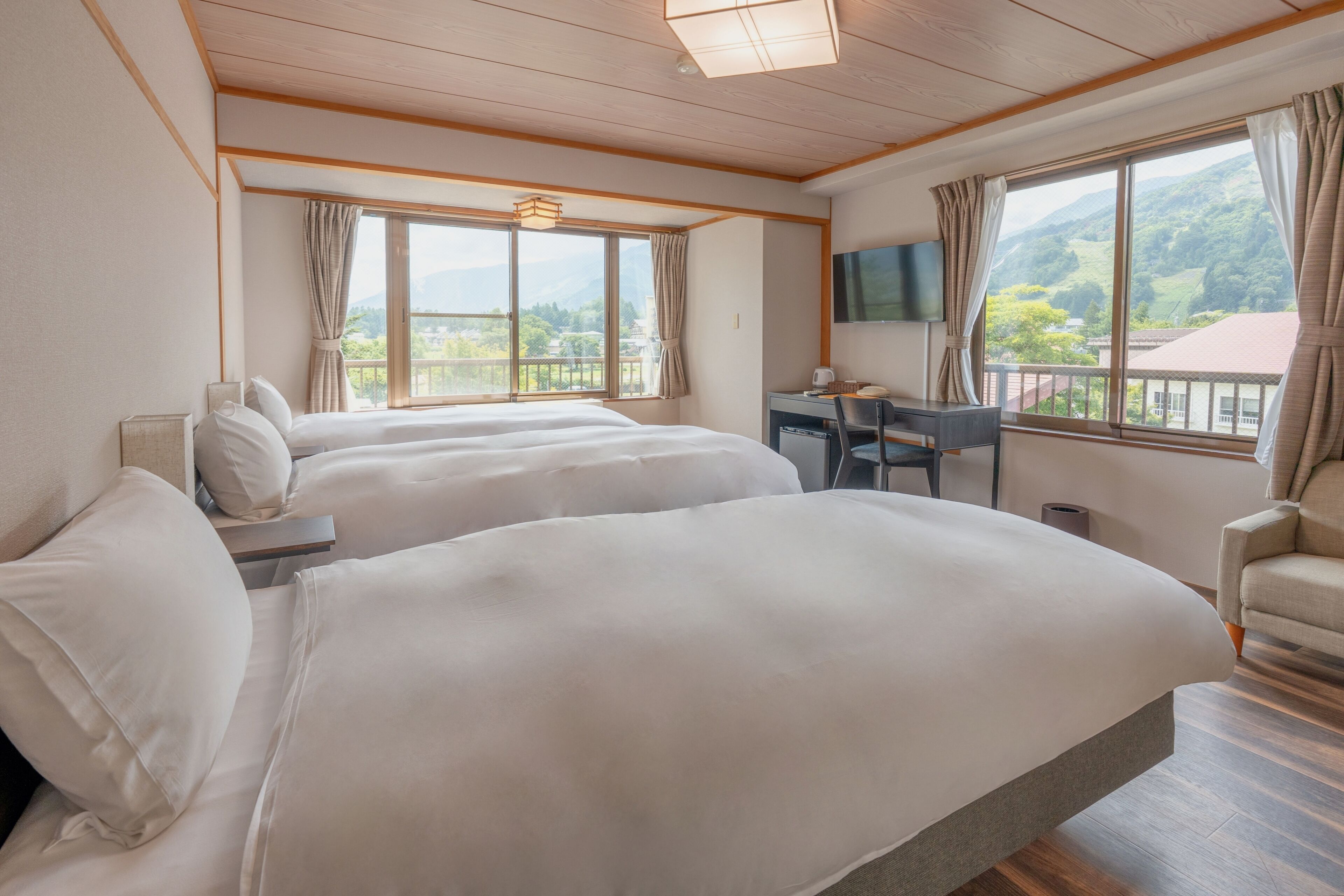 Ein Hotelzimmer mit zwei Betten, einem Schreibtisch, einem Stuhl und einem Fernseher.