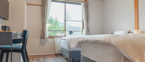 A bedroom with a bed, a desk with a chair, a window with curtains, and a radiator.