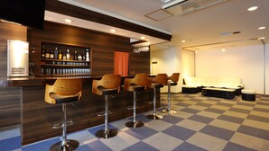 A bar area with a checkered floor, bar stools, a sofa, and a television. - SUMMIT VIEWS HAKUBA (Hakuba)