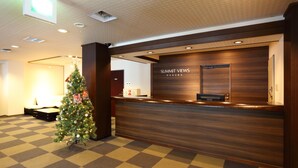 A reception desk with a wooden finish and a sign that reads "Summit Views Hakuba". There is a Christmas tree with lights and ornaments next to the desk. - SUMMIT VIEWS HAKUBA (Hakuba)