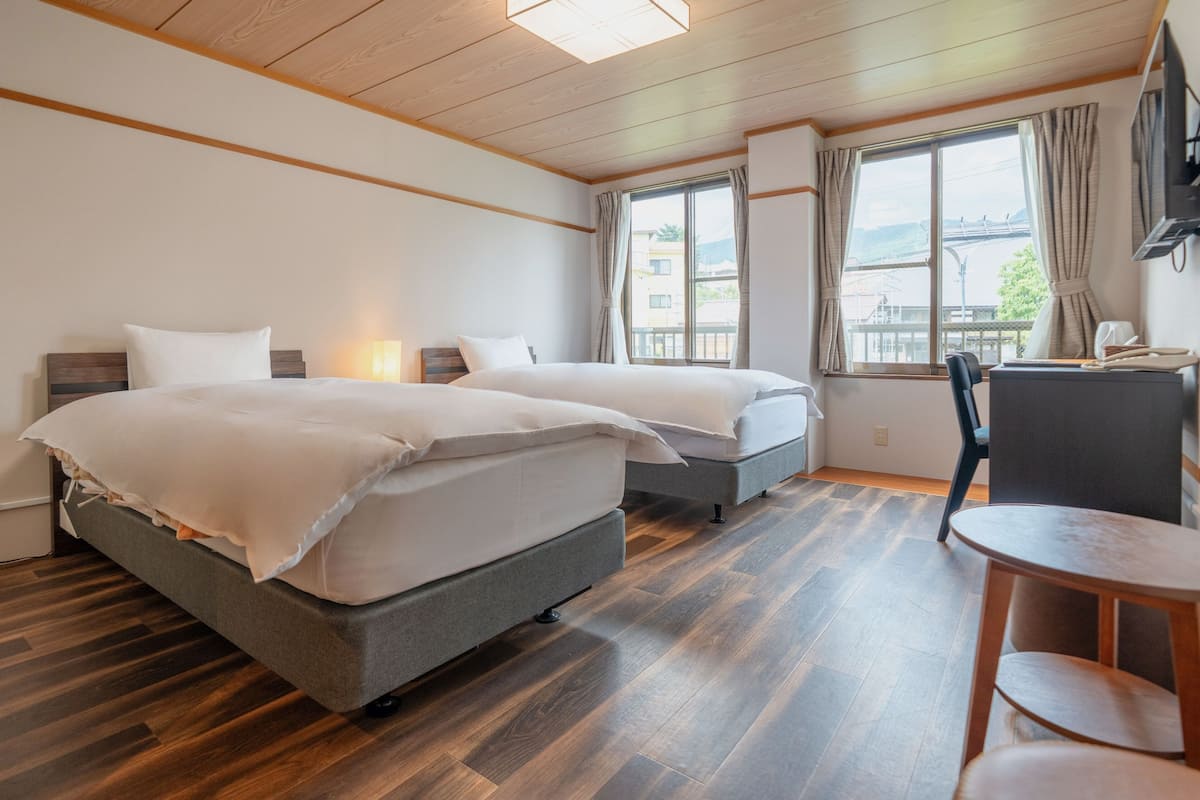 A hotel room with two beds, a desk, and a chair.
