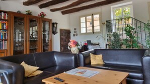 Ein Wohnzimmer mit schwarzem Ledersofa, Couchtisch aus Holz und Bücherregal.