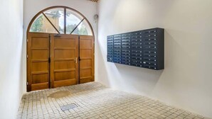 A hallway with a wooden double door and a wall-mounted mail slot. - Stylish Studio in the Center of Poznań | Balcony | Close to MTP (Poznan)