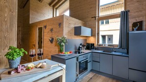 Una cocina moderna con vigas de madera, horno empotrado y un amplio ventanal con cortinas.