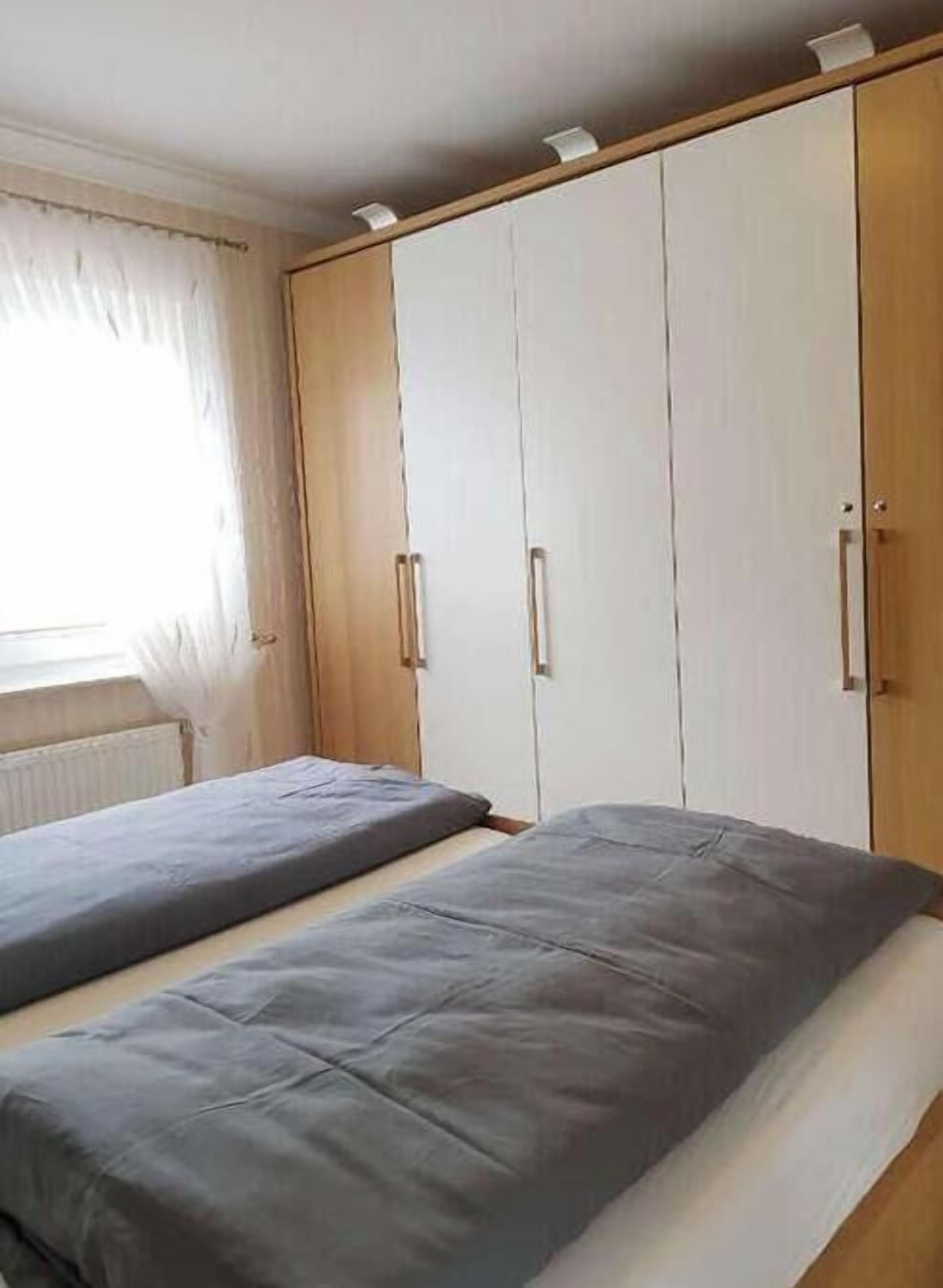 Ein Schlafzimmer mit zwei Betten, einem Kleiderschrank und einem Fenster mit Vorhängen.
