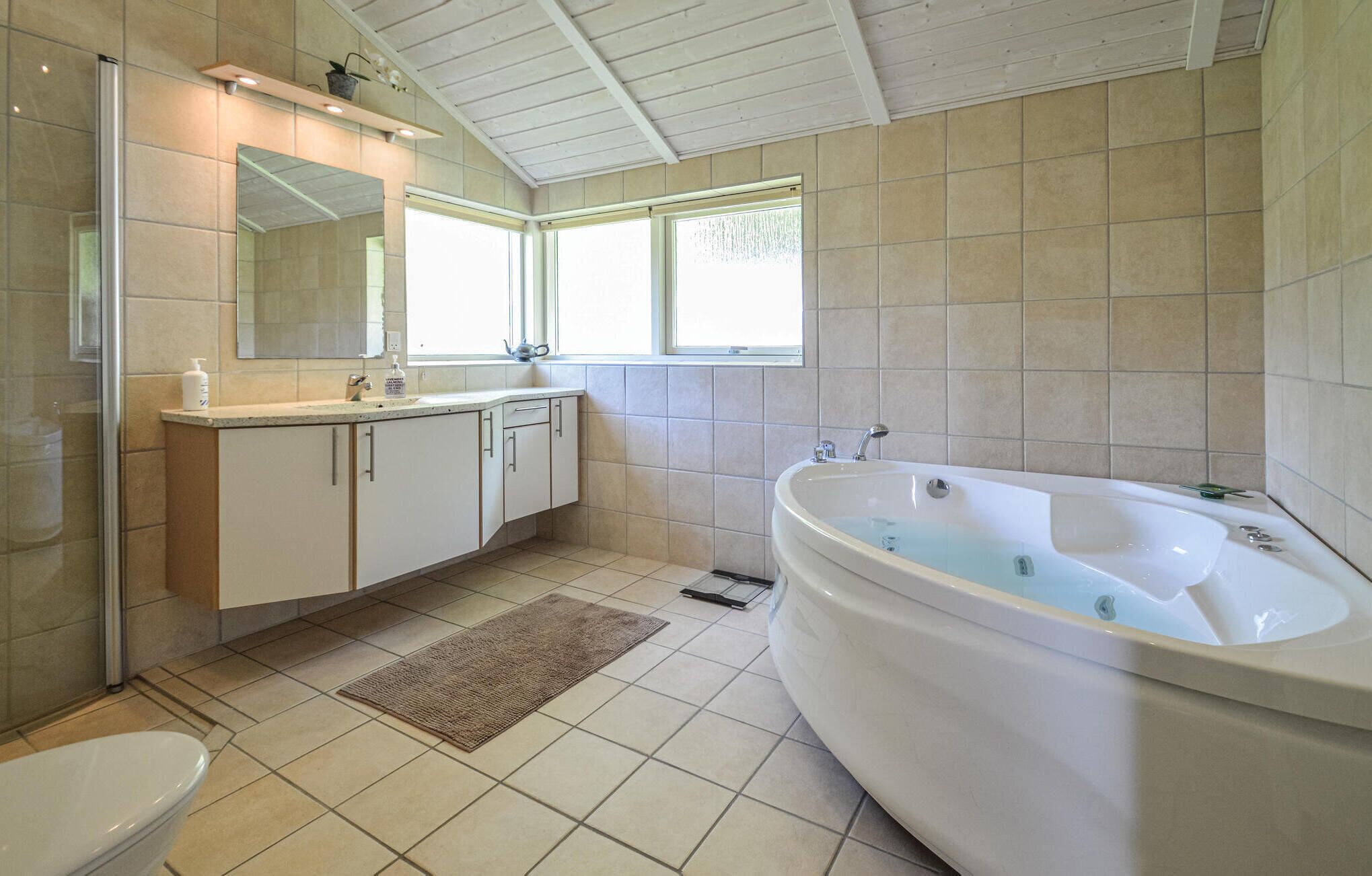 Un baño moderno con una bañera grande, una ducha a ras de suelo y un inodoro.