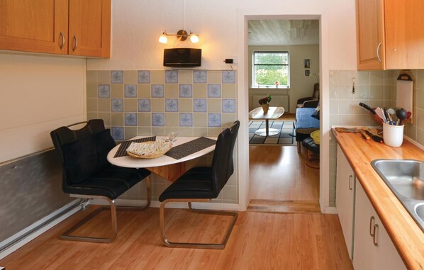 A compact kitchen with a dining area, wooden cabinets, a microwave, and a tiled backsplash. - Cozy apartment in Sønderborg with WiFi (Sønderborg)