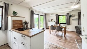 Une cuisine moderne dotée d’un plan de travail en bois, de meubles blancs et d’un coin repas avec une table et des chaises.