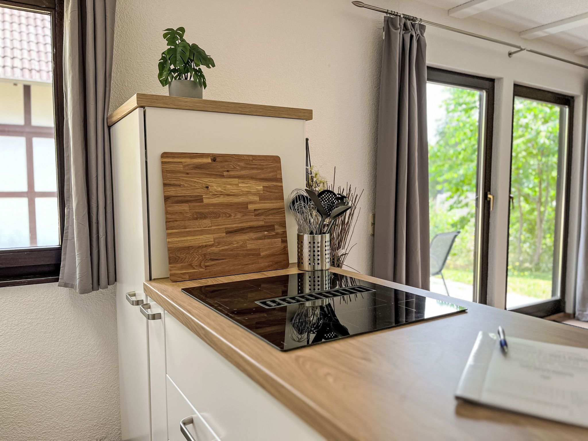 Een moderne keuken met een houten aanrechtblad, een inbouwfornuis en een plant in een pot op de vensterbank.