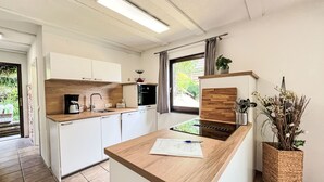 Une cuisine moderne avec des armoires blanches, un plan de travail en bois et une cuisinière intégrée.
