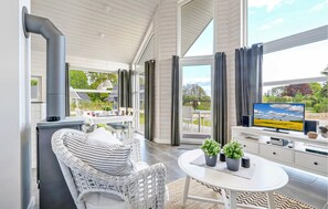 Una sala de estar moderna con chimenea, comedor y televisor sobre un mueble blanco.