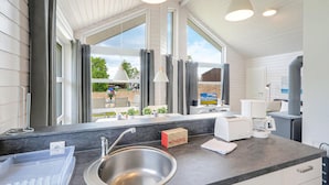 Een moderne keuken met een groot raam, een spoelbak en een koffiezetapparaat.