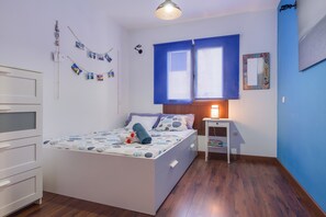 A bedroom with a bed, bedside table, and a window with blue blinds.