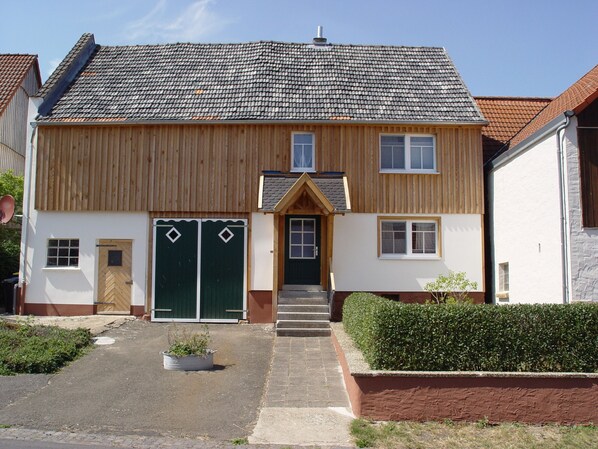 A two-story house with a hipped roof, a front entrance with double doors, and a small front garden.