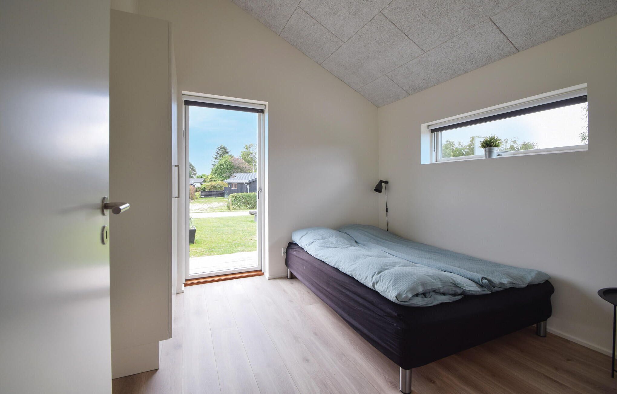 Ein Schlafzimmer mit Bett, Fenster und einer Tür, die auf einen Balkon führt.