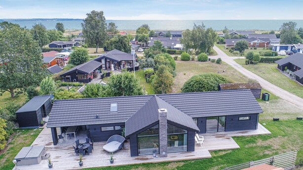A modern house with a large deck, a covered outdoor seating area, and a view of the sea. - Lovely home in Juelsminde with WiFi (Juelsminde)