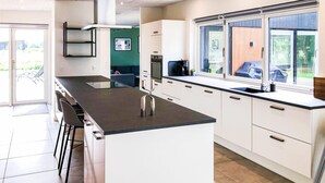 Eine moderne Küche mit weißen Schränken, einer schwarzen Arbeitsplatte und einem Fenster mit Blick ins Freie.