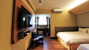 Une chambre d’hôtel équipée d’un lit, d’un téléviseur fixé au mur, d’un bureau avec une chaise et d’un appareil de climatisation.