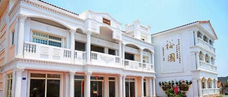Un edificio blanco de varios pisos con balcones y ventanas amplias.