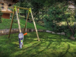 A wooden swing set in a grassy backyard with a tennis racket hanging from one of the swings. - Chalet Hollygotty - luxury base for 8, spa, mountain views - OVO Network (La Clusaz)