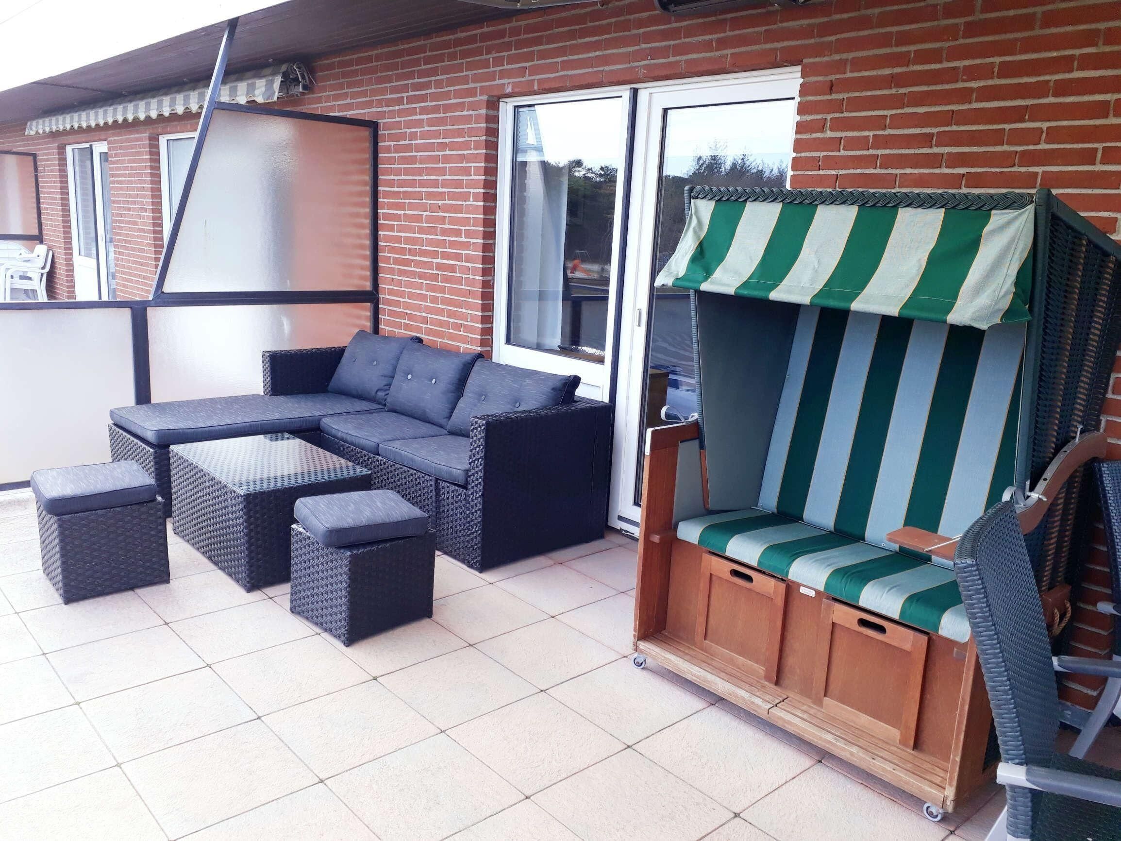 Un patio con un sofá modular, una mesita y una silla a rayas.