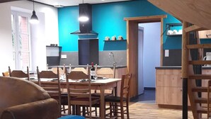 Uma sala ampla com uma mesa de jantar, cadeiras, um sofá e um lance de escadas.