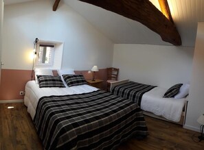 Una camera da letto con due letti, una finestra, un soffitto in legno e un comodino con una lampada.