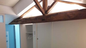 Quarto com teto de madeira, cama com roupa de cama listrada e closet espaçoso.