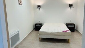 Quarto com uma cama, duas mesas de cabeceira, uma luminária na parede e um radiador.