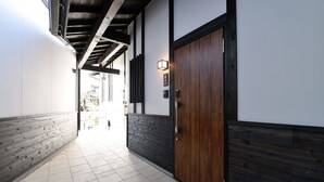 A hallway with a wooden door, a light fixture, and a view into another room. - Hinata-an (Yufu)