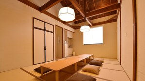 A traditional Japanese room with tatami flooring, a low wooden table, cushions, and a sliding door. - Hinata-an (Yufu)