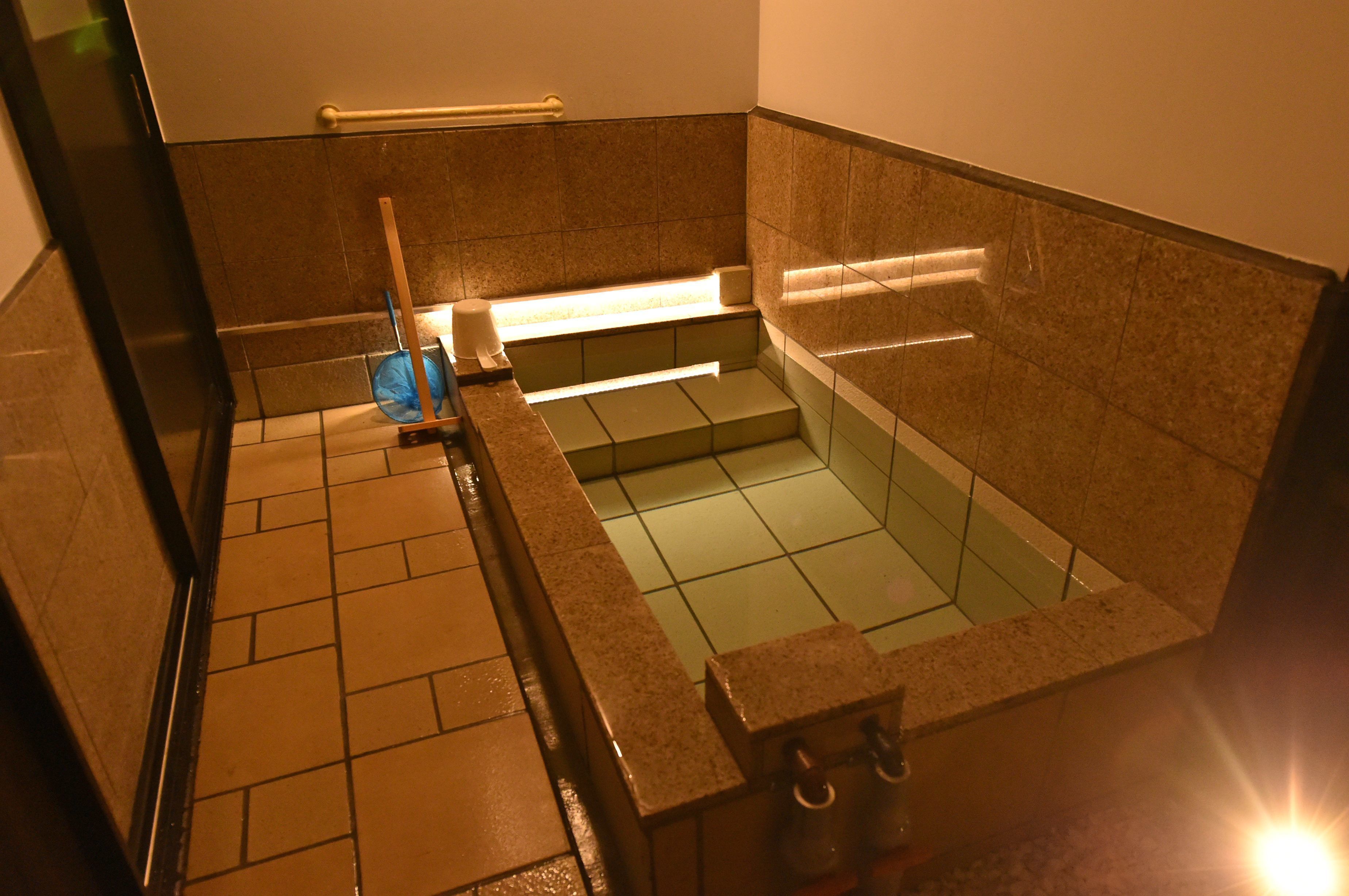 A small, tiled bathroom with a bathtub, a toilet, and a shower area.