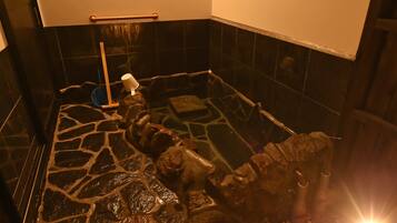 A stone-floored bathroom with a handrail and a mop.