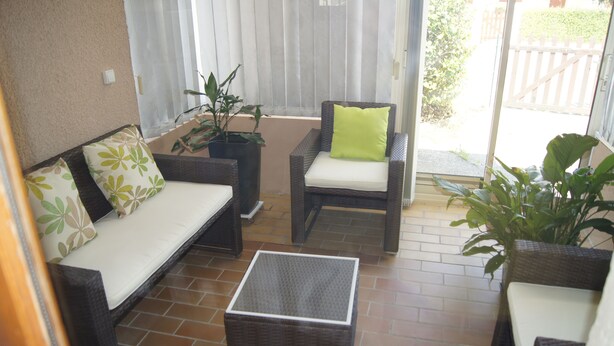 A patio area with wicker furniture, including a sofa and chairs, and a small table. - Furnished holiday home with garden (Gujan-Mestras)