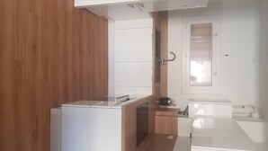 Eine kompakte Küche mit einer Wandpaneele aus Holz, einem eingebauten Backofen und einer kleinen Arbeitsplatte.