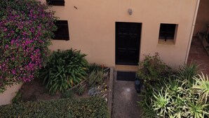 A building with a tiled roof, a small garden with various plants, and a view of the sea and mountains in the background. - Little Villa "La Maredda" in Porticcio with sea view terrace and beach at 250m! (Porticcio-Grosseto-Prugna)