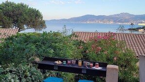 A terrace with a table set for two, overlooking a coastal cityscape with mountains in the distance. - Little Villa "La Maredda" in Porticcio with sea view terrace and beach at 250m! (Porticcio-Grosseto-Prugna)