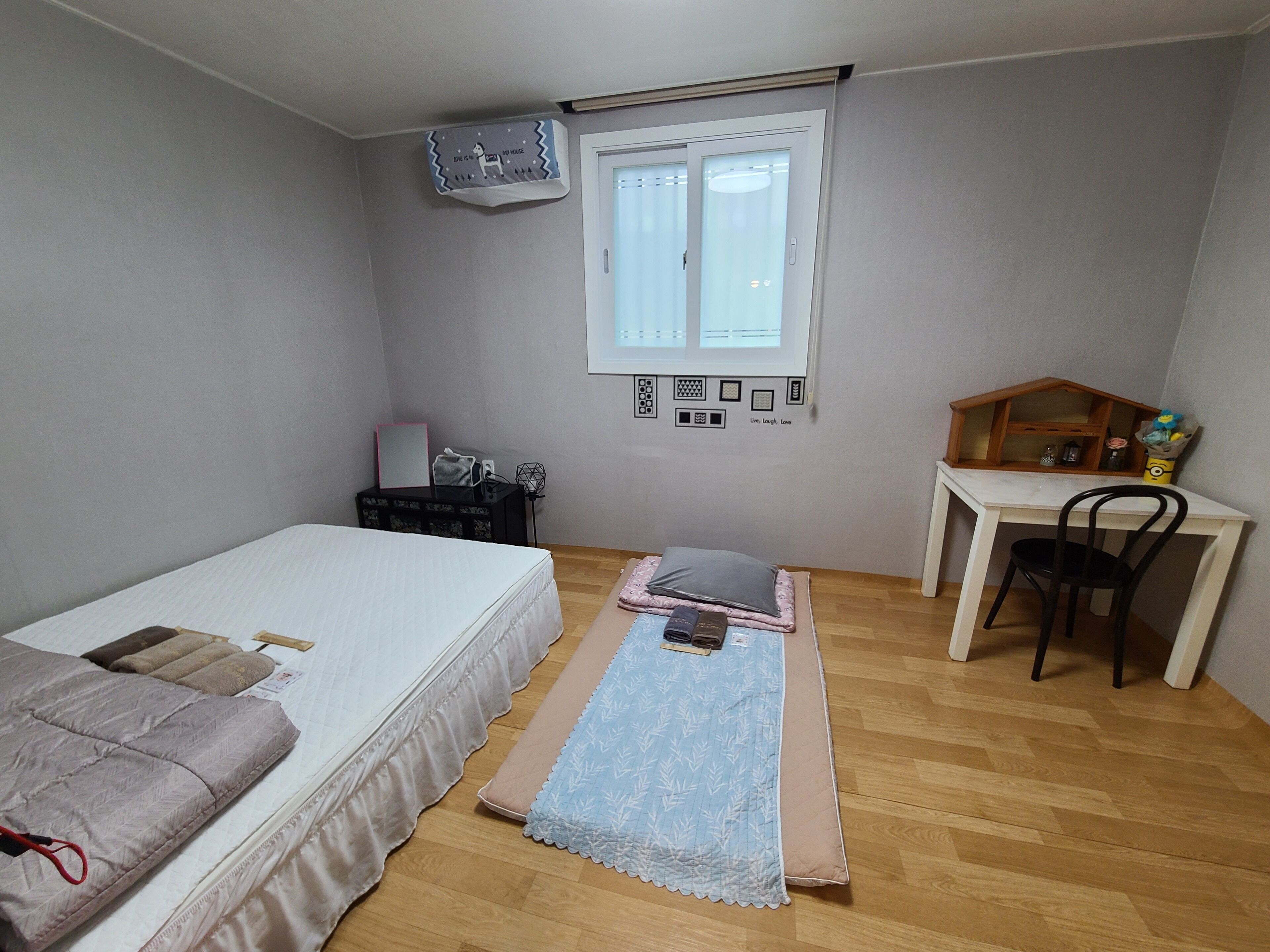 A bedroom with a bed, a desk, and a small window.