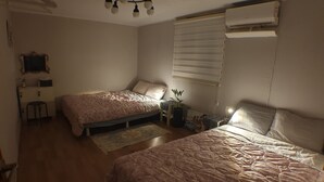 A bedroom with two beds, a desk, a chair, a potted plant, and an air conditioning unit. - YeoU (Mungyeong)