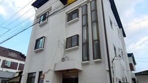 A white two-story building with a black door and windows, a small front porch, and visible electrical wiring. - YeoU (Mungyeong)