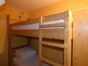 Un lit superposé avec une structure en bois, un matelas blanc et un oreiller.