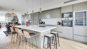 A modern kitchen with a central island, bar stools, and stainless steel appliances.