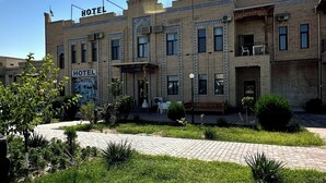 A hotel with multiple stories, featuring a traditional brick facade and a prominent "UMAR" sign on the top. - Hotel UMAR (Khiva)