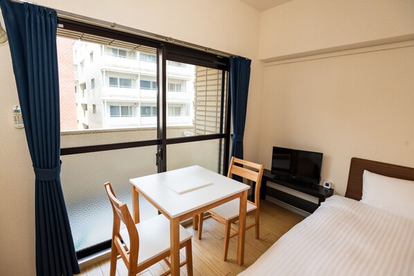 A hotel room with a bed, a TV, a small table, and two chairs. - Hotel Chaika in Fukuoka (Fukuoka)